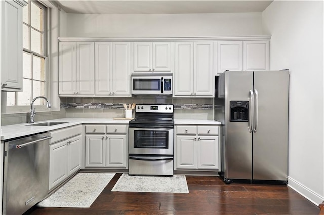 kitchen featuring a sink, light countertops, stainless steel appliances, backsplash, and dark wood-style floors