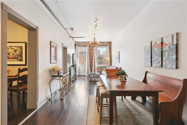 dining room with baseboards, rail lighting, a chandelier, and dark wood-type flooring