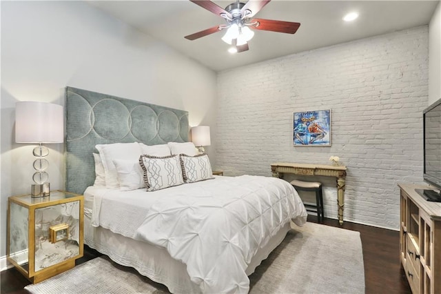bedroom with ceiling fan, wood finished floors, and brick wall