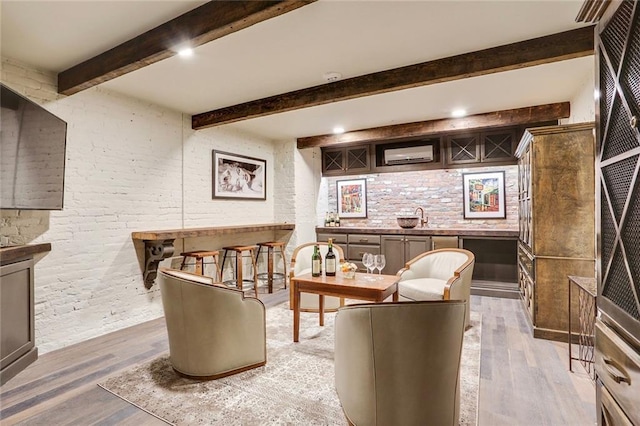 interior space with a sink, bar area, beam ceiling, and light wood-style flooring