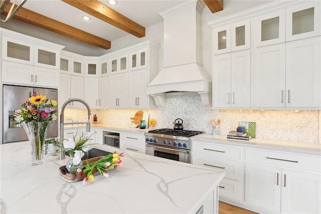 kitchen with stainless steel appliances, recessed lighting, white cabinetry, custom range hood, and beamed ceiling