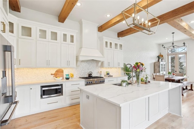 kitchen featuring appliances with stainless steel finishes, a sink, beam ceiling, a chandelier, and tasteful backsplash