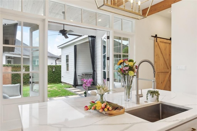 interior space featuring a ceiling fan, light stone countertops, a healthy amount of sunlight, and a sink