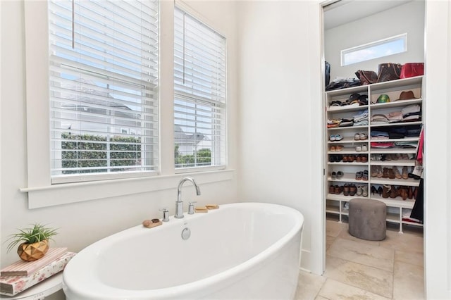 bathroom featuring a freestanding tub and a walk in closet