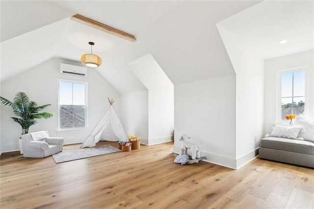 additional living space featuring an AC wall unit, wood finished floors, a wealth of natural light, and vaulted ceiling