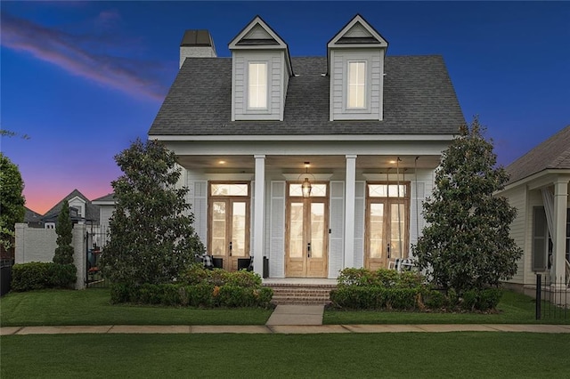 view of front facade featuring fence, roof with shingles, french doors, a lawn, and a porch
