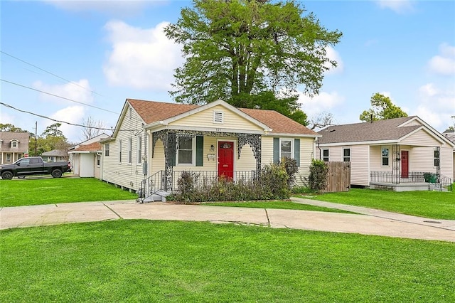 bungalow-style home featuring covered porch, a shingled roof, a front lawn, and driveway