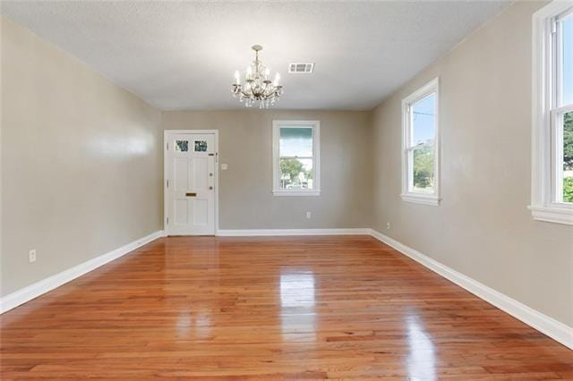 unfurnished dining area with a chandelier, light wood finished floors, healthy amount of natural light, and baseboards