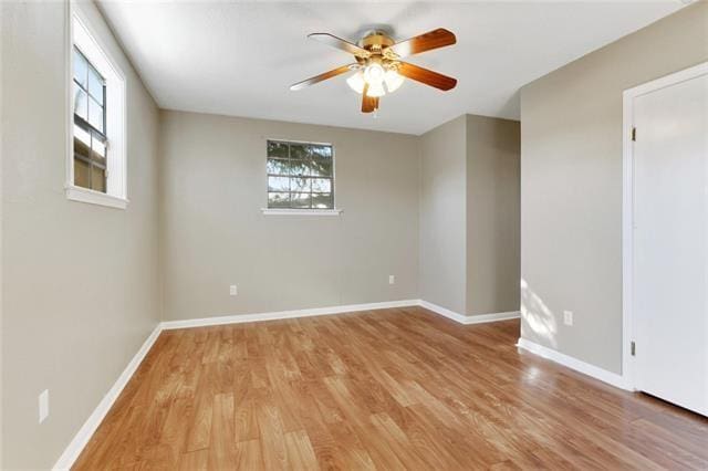 empty room featuring a ceiling fan, light wood-type flooring, and baseboards