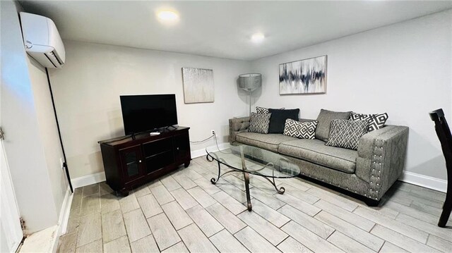 living room with an AC wall unit, baseboards, and wood finished floors