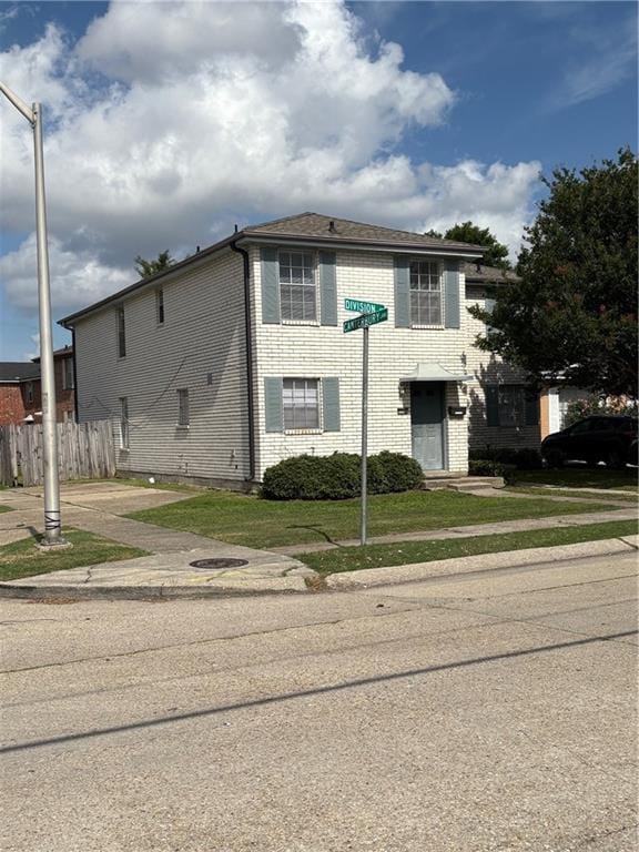 220002 Division St, Metairie, LA 70001 - view of front facade featuring fence, a front yard, and brick siding