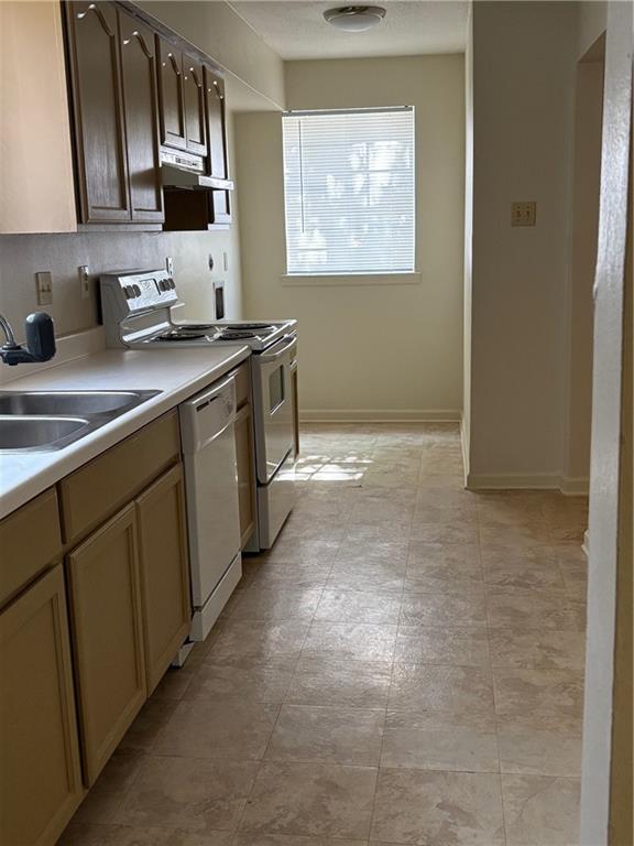 220002 Division St, Metairie, LA 70001 - kitchen with a sink, white appliances, light countertops, baseboards, and under cabinet range hood