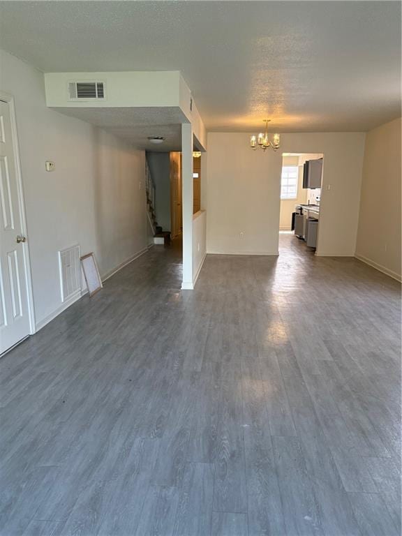 220002 Division St, Metairie, LA 70001 - unfurnished living room with baseboards, visible vents, an inviting chandelier, and dark wood-type flooring