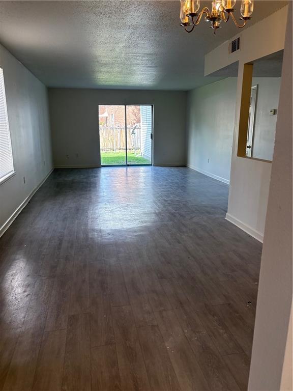 220002 Division St, Metairie, LA 70001 - unfurnished room featuring visible vents, an inviting chandelier, baseboards, a textured ceiling, and dark wood finished floors