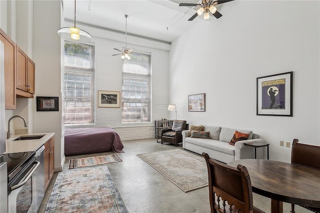 living room featuring a ceiling fan, a high ceiling, and concrete flooring