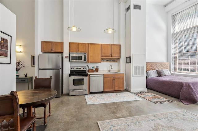 kitchen with a sink, concrete flooring, a high ceiling, and stainless steel appliances