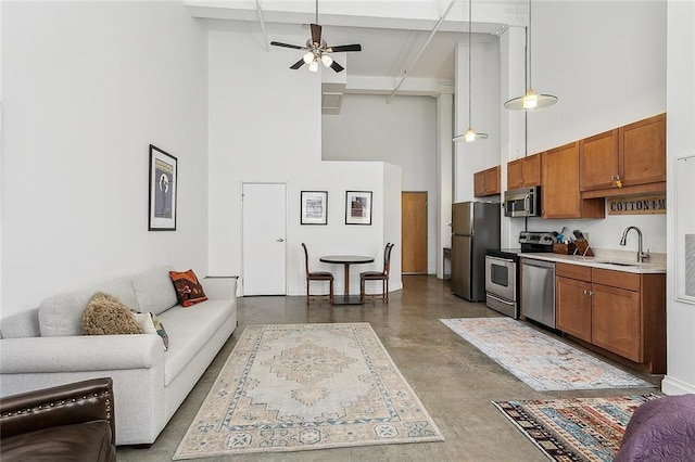 living room featuring beamed ceiling, concrete flooring, ceiling fan, and a towering ceiling