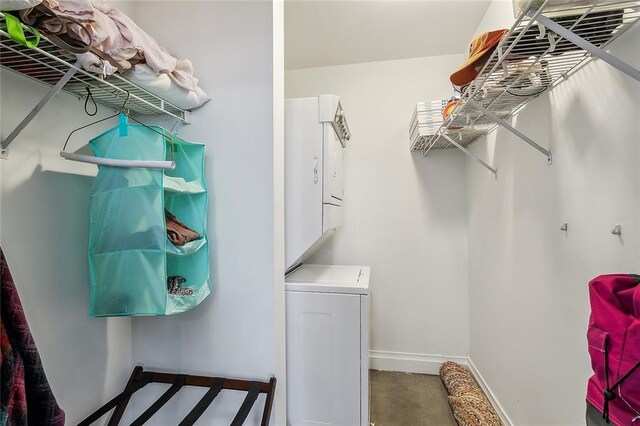 clothes washing area with laundry area, baseboards, and stacked washer / drying machine