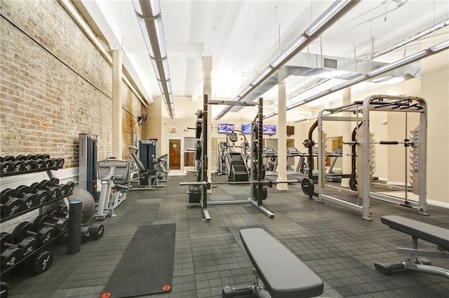 gym with brick wall and a towering ceiling