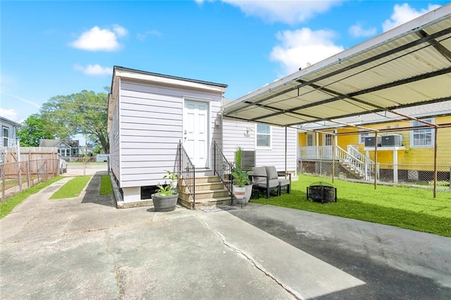 rear view of house featuring a detached carport, fence, a yard, and entry steps