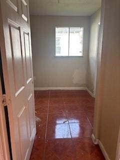 corridor with baseboards and tile patterned floors