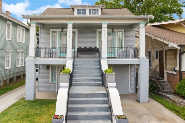 view of front of home with roof with shingles, covered porch, and stairway