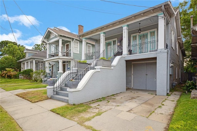 view of property featuring an attached garage, covered porch, stairway, and concrete driveway