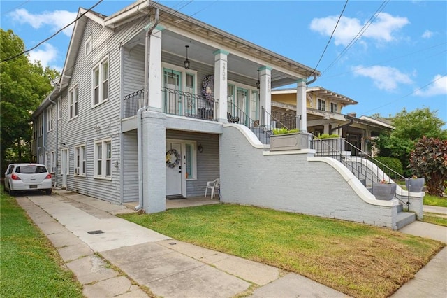 view of front of property with stairs, driveway, a porch, and a front lawn