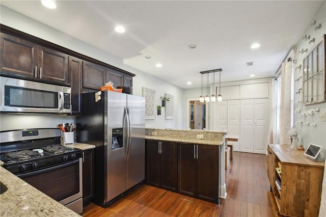 kitchen featuring dark brown cabinetry, appliances with stainless steel finishes, light stone counters, a peninsula, and dark wood-type flooring