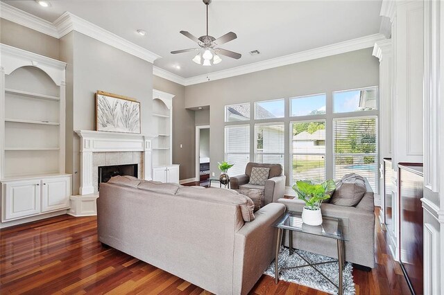 864 Sweet Bay Dr, Mandeville, LA 70448 - living area featuring built in features, ceiling fan, dark wood-type flooring, a tile fireplace, and crown molding