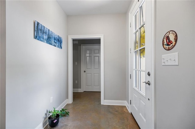 hall featuring finished concrete floors and baseboards