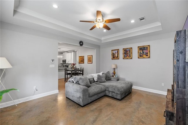 living room with a ceiling fan, visible vents, concrete floors, and a raised ceiling