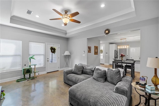 living area featuring ceiling fan, finished concrete floors, visible vents, a raised ceiling, and baseboards