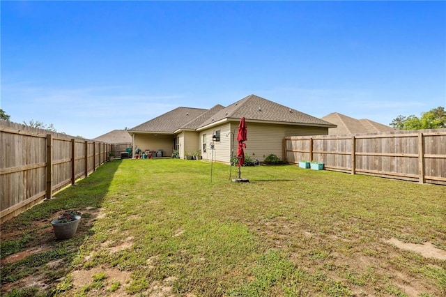 rear view of house with a lawn and a fenced backyard