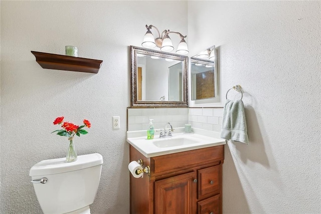 bathroom featuring vanity, backsplash, and toilet
