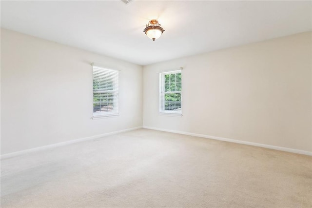 unfurnished room featuring baseboards and light carpet
