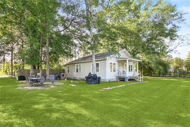 rear view of property featuring a lawn, fence, and a porch