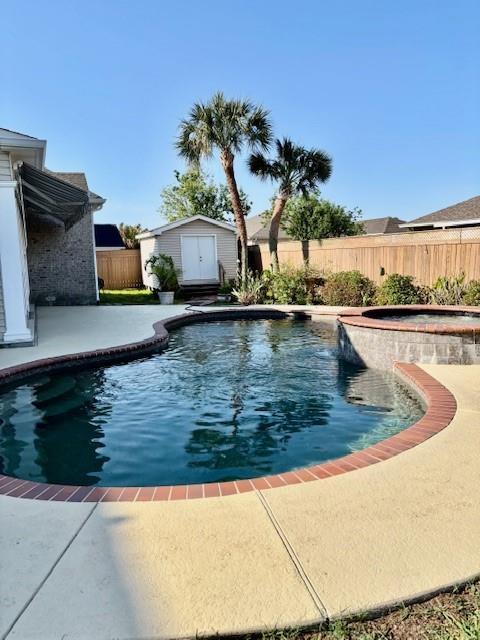 view of pool with fence, a patio, a fenced in pool, an in ground hot tub, and a storage shed