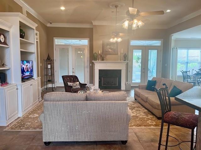 tiled living room featuring a ceiling fan, french doors, crown molding, a fireplace, and recessed lighting