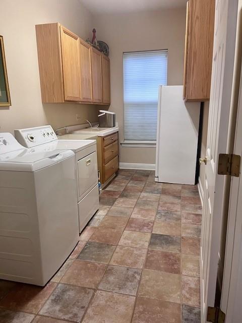 laundry area featuring baseboards, washing machine and dryer, stone finish flooring, and cabinet space