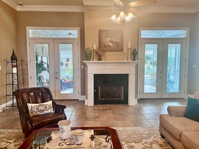 tiled living area with french doors, ornamental molding, baseboards, and a ceiling fan