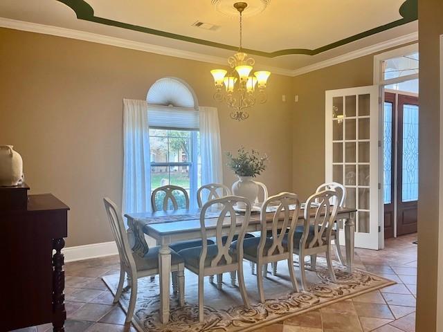 dining area featuring crown molding, a chandelier, baseboards, a tray ceiling, and visible vents