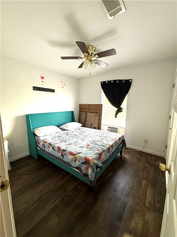 bedroom with baseboards, a ceiling fan, dark wood finished floors, and visible vents
