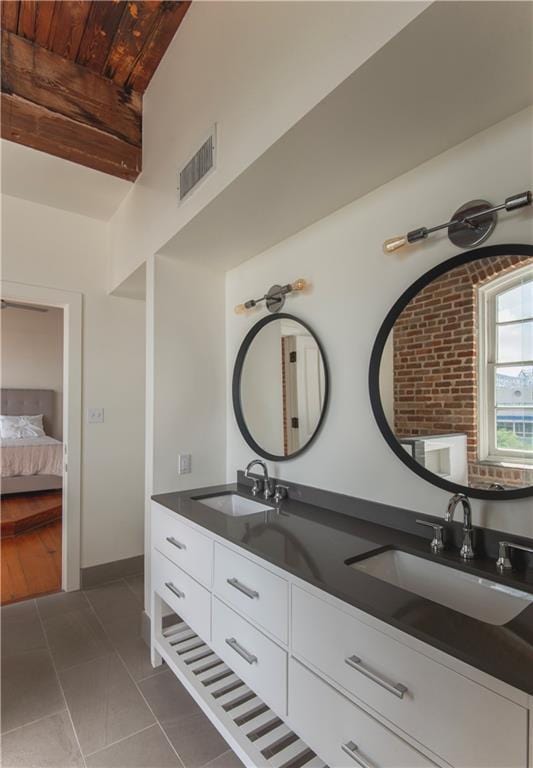 ensuite bathroom featuring a sink, tile patterned floors, ensuite bathroom, and double vanity