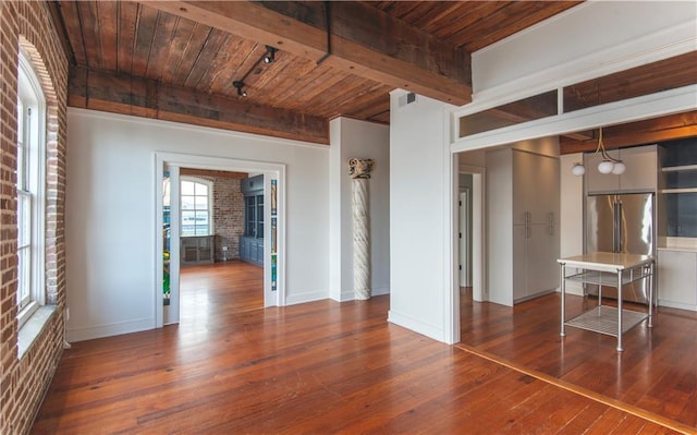unfurnished living room featuring hardwood / wood-style floors, baseboards, wooden ceiling, beamed ceiling, and visible vents