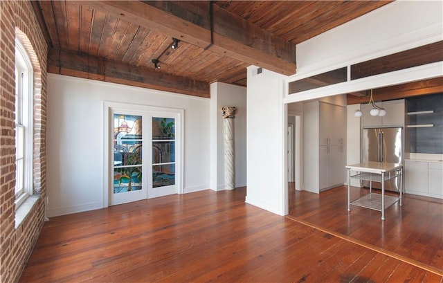 unfurnished living room featuring track lighting, beam ceiling, baseboards, wood ceiling, and hardwood / wood-style flooring