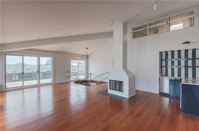 unfurnished living room with baseboards, a high ceiling, wood finished floors, and a notable chandelier