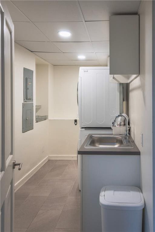 washroom featuring electric panel, a sink, baseboards, stacked washer and clothes dryer, and recessed lighting