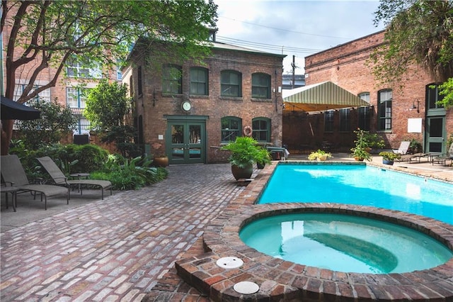 view of swimming pool with a patio area, a pool with connected hot tub, and french doors