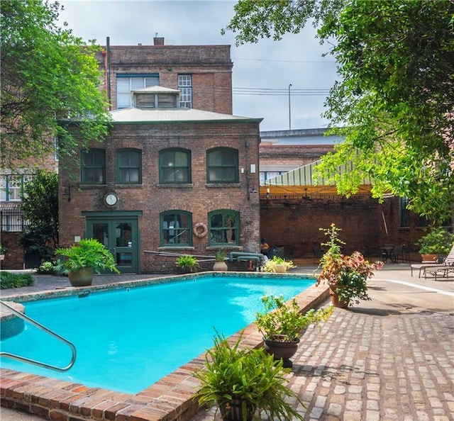 pool with french doors and a patio area
